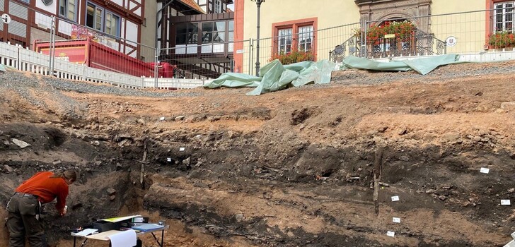 Das Foto zeigt den Archäologen Benedikt König in der Baugrube auf dem Marktplatz bei der Ausgrabung archäologischer Funde.