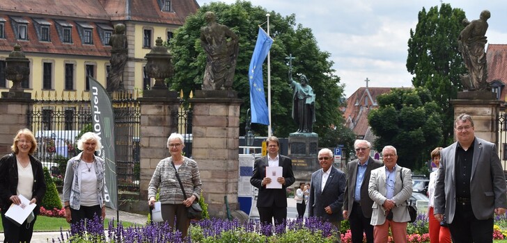 Fröhliches Gruppenbild im Ehrenhof des Stadtschlosses. Der Oberbürgermeister präsentiert stolz die Auszeichnung.