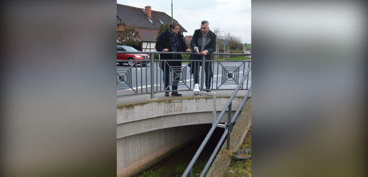 Bürgermeister Benjamin Tschesnok und Jovica Smiljkovic von der Firma EDAG bei einem Ortstermin in Roßbach, wo ein Radarsensor zur Überwachung des Roßbachs eingebaut wurde.