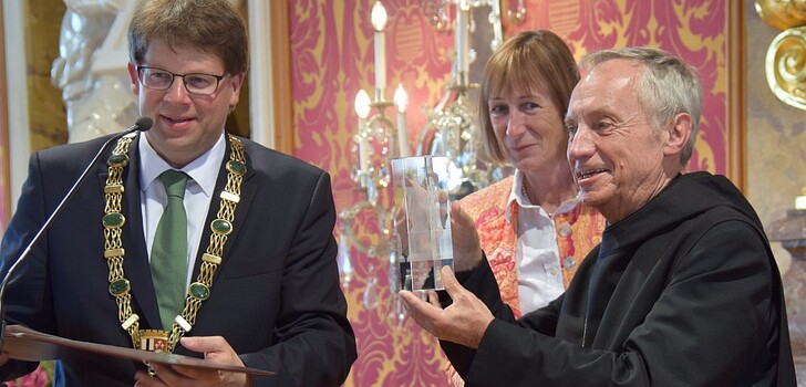 Abtprimas Notker Wolf zeigt den Winfriedpreis, den er von Bettina Langer, der Tochter des Stifters, und OB Heiko Wingenfeld bekommen hat.