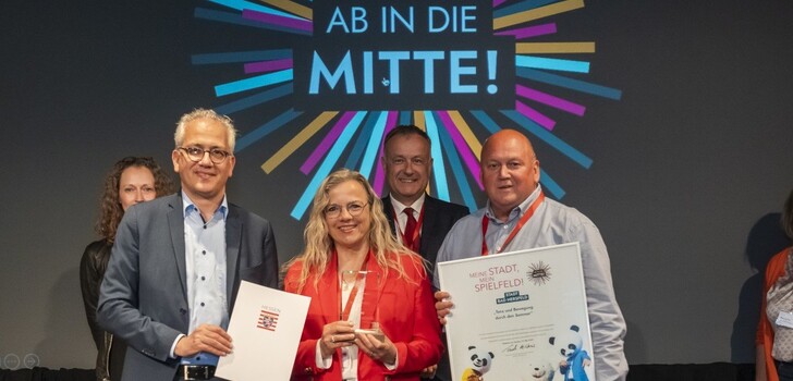 Tarek Al Wazir, der Hessische Minister für Wirtschaft, Energie, Verkehr und Wohnen, übergibt den Förderbescheid an Jutta Hendler und Markus Heide.