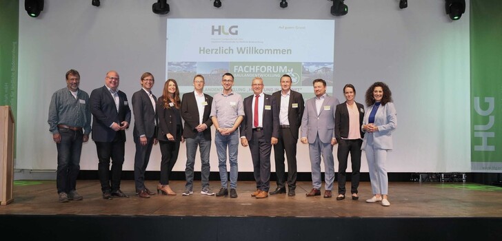 Von links nach rechts: Dr. Matthias Peter (Ingenieurbüro Schnittstelle Boden), Bürgermeister Stadt Alsfeld Stephan Paule, Staatssekretär Jens Deutschendorf (HMWEVW), Tamara Hintermeier (WIBank), Patrick Kucharski (HLG), Lukas Sittel (Sittel Energieberatung), Geschäftsführer Dr. Gerald Kunzelmann (HLG), Andreas Gerhard (HLG), Dr. Michael Stroh (HLG), Prof. Dr. Tine Köhler (Professur für Landmanagement FRA UAS), Evren Gezer (Moderatorin).