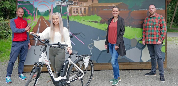 Die vorher langweilige Schutzhütte am ehemaligen Bahnhof in Hilders ist künstlerisch von Ingmar Süß (links) aufgewertet worden. Larissa Kempf (Gemeinde Hofbieber), Katharina Lubosz (Marktgemeinde Hilders) und Sebastian Kircher (Gemeinde Petersberg) hoffen, dass viele Radler die Hütte nun als Selfie-Point entdecken werden.