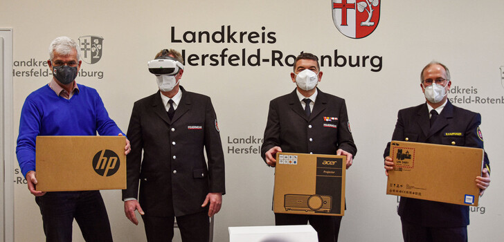 Bildunterschrift: Neue Technik für die Feuerwehrausbildung im Kreis Hersfeld-Rotenburg: Der stellvertretende Verbandsvorsitzender Guido Kamm (Mitte) übergab Landrat Torsten Warnecke (links) und Kreisbrandinspektor Marco Kauffunger (rechts) die Spende von zwei Notebooks und einem Beamer. Der Vorsitzende des Kreisfeuerwehrverbands Thomas Specht (2. von links) probierte indessen die Virtual-Reality-Brille für die digitale Simulation gleich selbst aus.