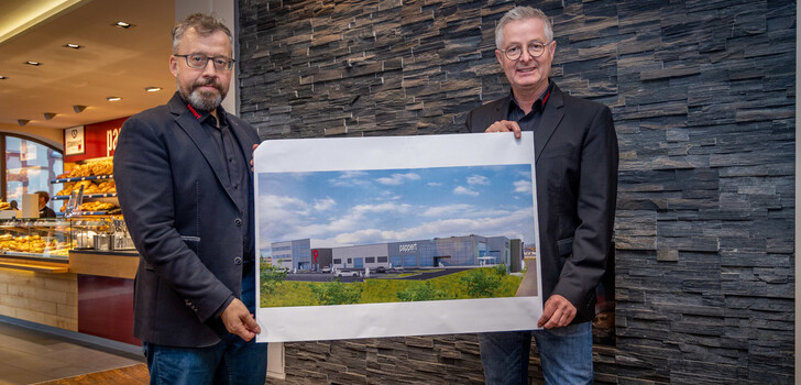 Die Geschäftsführer Bernd Pappert (l) und Manfred Klüber (r) im Stammhaus mit der Visualisierung des neuen Backhauses