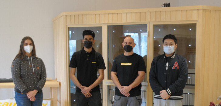 Saunalux-Geschäftsführer Hao Jin und Prokuristin Isabell Wißner mit Musa Hammadi und Josè Miguel Guerrero Torres (Mitte) vor einer Sauna im Ausstellungsraum