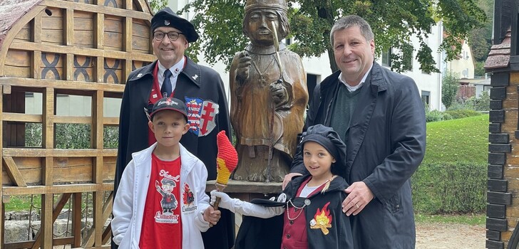Mit Feuermeister und Bürgermeister im Hintergrund: Ian übergibt symbolisch die Lolls-Fackel an seine Nachfolgerin Miley.